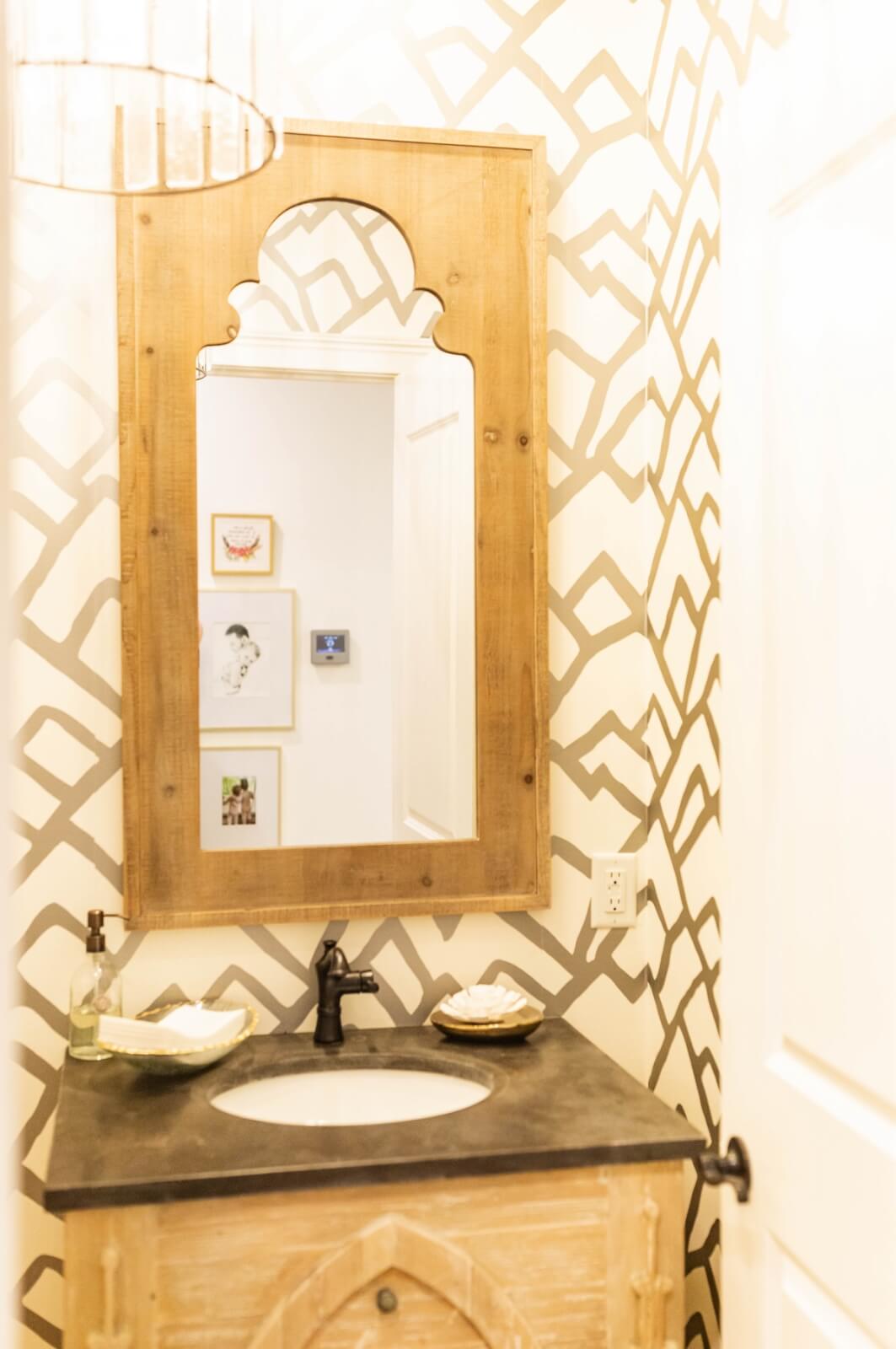 Powder room with patterned wallpaper and wood mirror