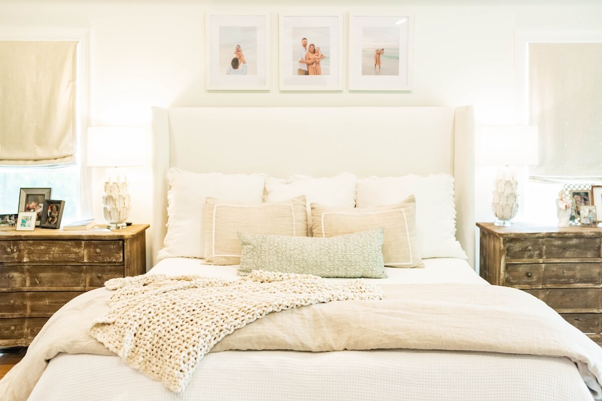 Primary bedroom with cream pillows and family photos above bed