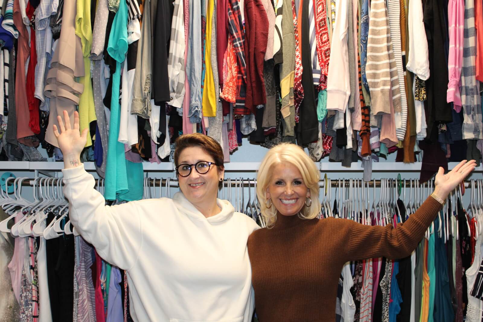 Two women in front of clothing