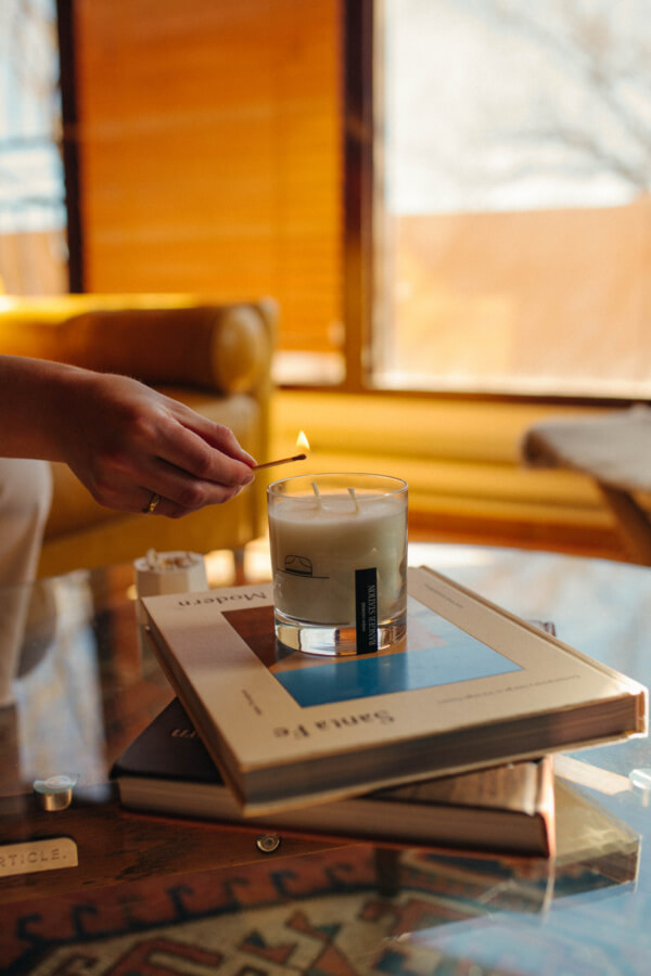 Someone lighting a candle atop a stack of books