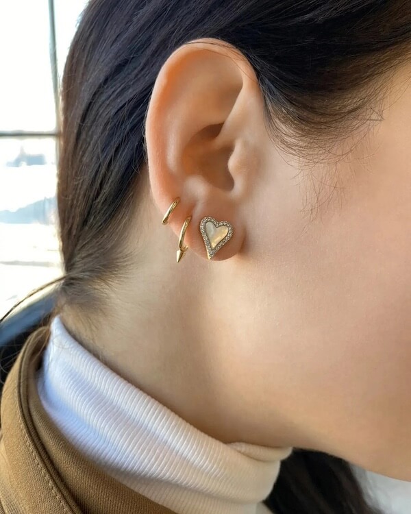 In a style reminiscent of Southern charm, the person dons multiple gold earrings in the left ear, featuring a heart-shaped one alongside two small curved pieces. It's a look perfect for February's romantic vibes and sophisticated elegance.