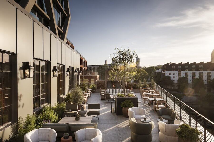 23 New Boutique Hotels in the South - 1 The rooftop terrace at this new boutique hotel features modern furniture and potted plants, all set against a breathtaking city skyline under the setting sun.