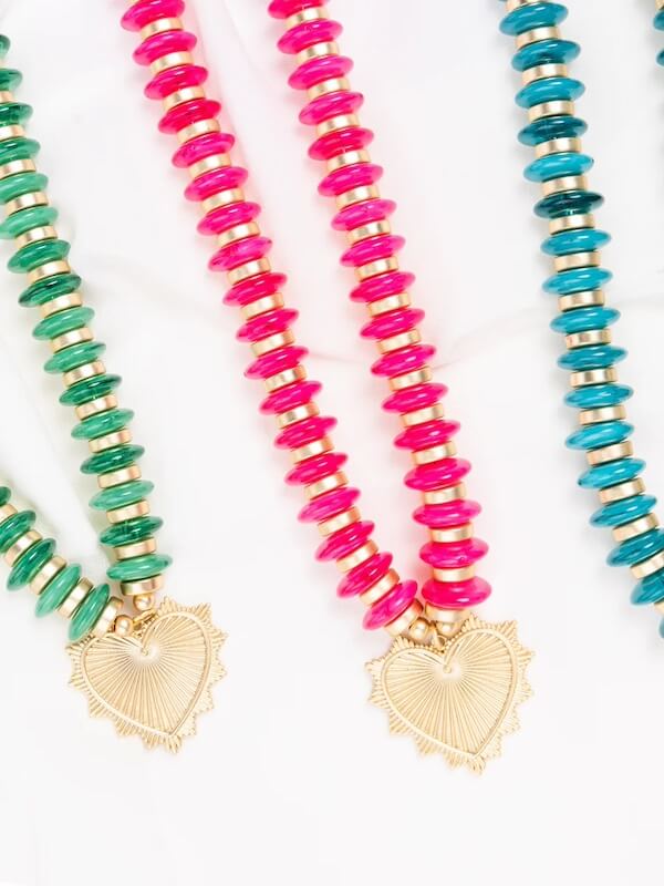 These Southern FINDS showcase three vibrant beaded necklaces with heart-shaped pendants against a white backdrop. The beads, in shades of green, pink, and turquoise, capture the playful spirit of February’s upcoming festivities.