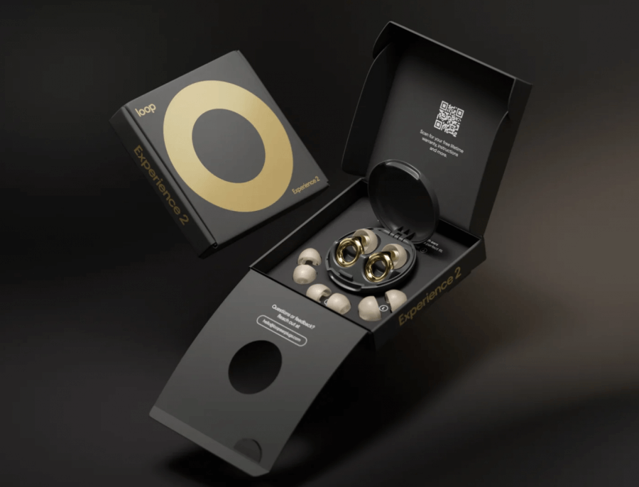 Open the black box of Loop Experience 2 earplugs, featuring a golden circle design and multiple interchangeable ear tips, perfect as the best travel accessory for sound clarity. Includes a QR code for easy access to features, all set against a sleek dark background.