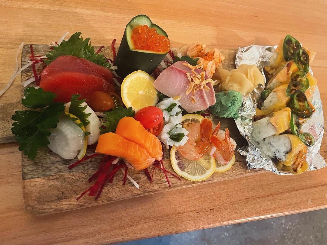 A wooden cutting board with a variety of sushi on it.