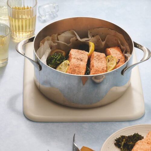 A pan with salmon and vegetables on a table.