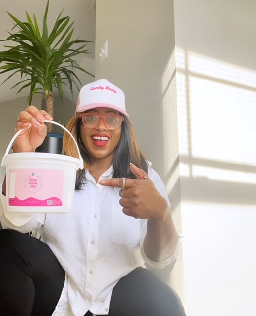 Woman in ball cap, pointing to a tub of cotton candy