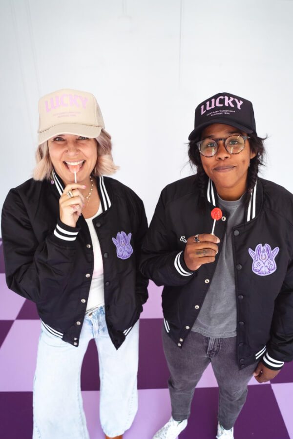 Allison Holley and Camille Alston in Lucky Rabbit caps, eating lollipops