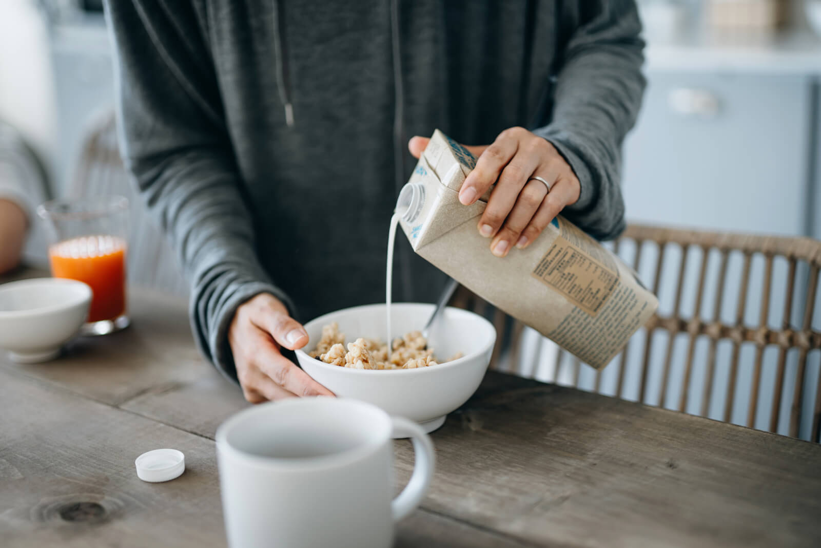 woman pouring milk over cereal on the kitchen counter. 