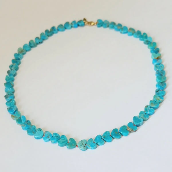 A February find, this turquoise necklace features heart-shaped beads arranged in a circle, beautifully displayed on a plain white surface.