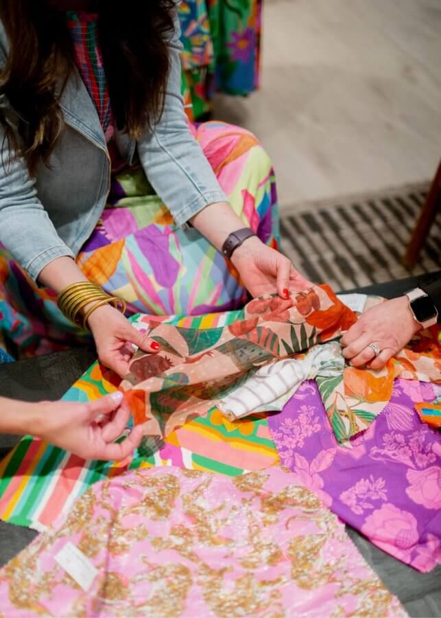A woman crouched down near colorful fabric.