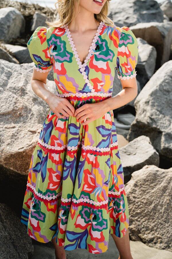 A woman in a colorful dress by rocks.
