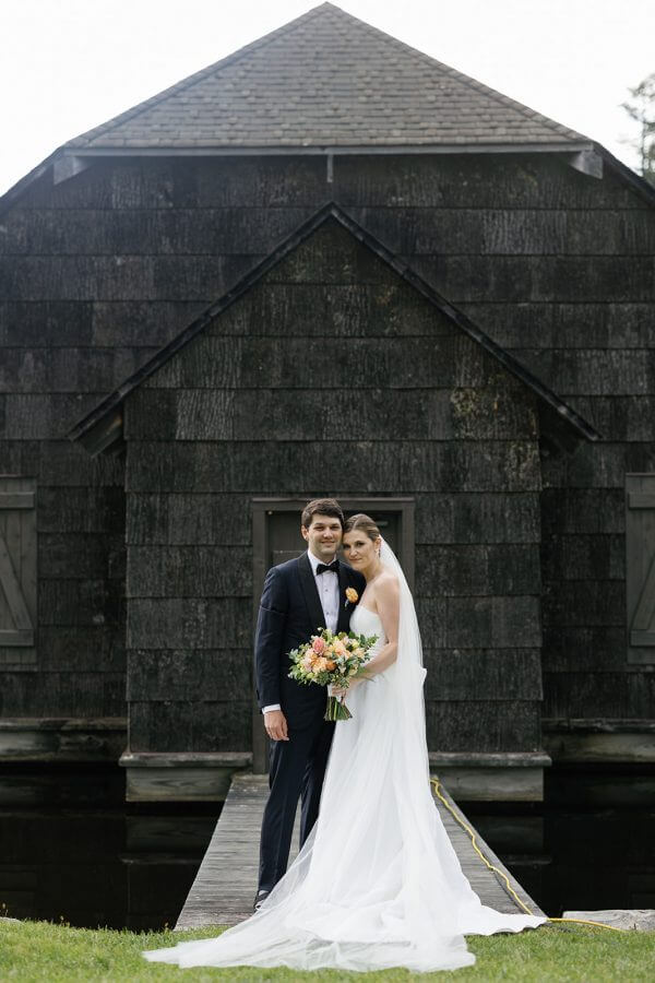 A North Carolina Wedding Dressed in Blues, Bows, and Bojangles - 3 A bride and groom standing in front of a black barn.