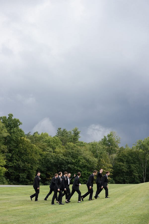 A North Carolina Wedding Dressed in Blues, Bows, and Bojangles - 12 A group of men in suits walking across a grassy field.