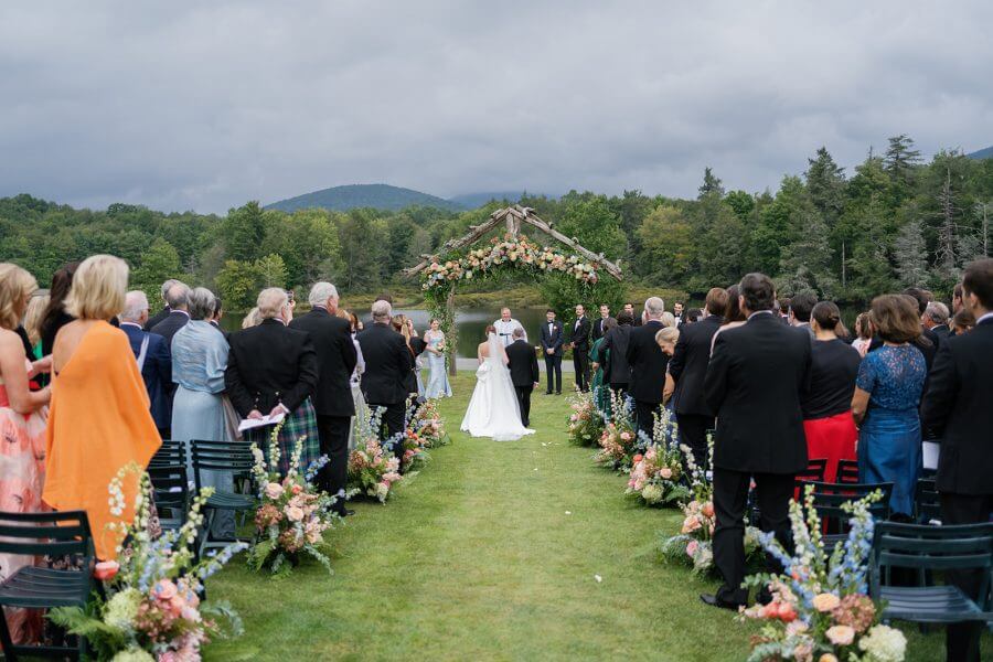 A North Carolina Wedding Dressed in Blues, Bows, and Bojangles - 16 A wedding ceremony in a grassy field with mountains in the background.