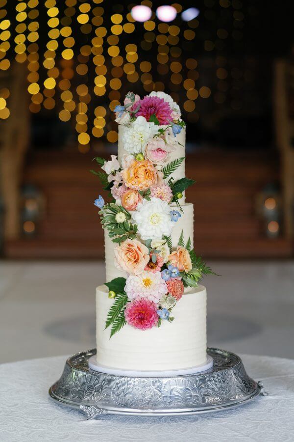 A North Carolina Wedding Dressed in Blues, Bows, and Bojangles - 21 A three-tier wedding cake with flowers on top.