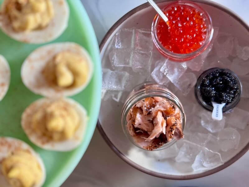 A deviled egg bar accompanied by small jars of red caviar and black caviar.