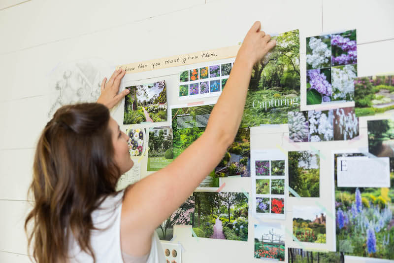 A woman is putting pictures on a wall.