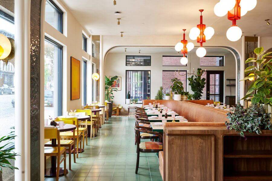 Modern restaurant interior with neatly arranged tables, pendant lighting, and a warm color palette.