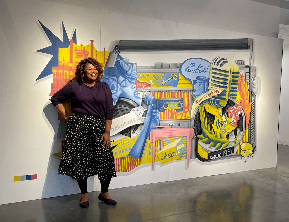 A woman standing in front of a mural.
