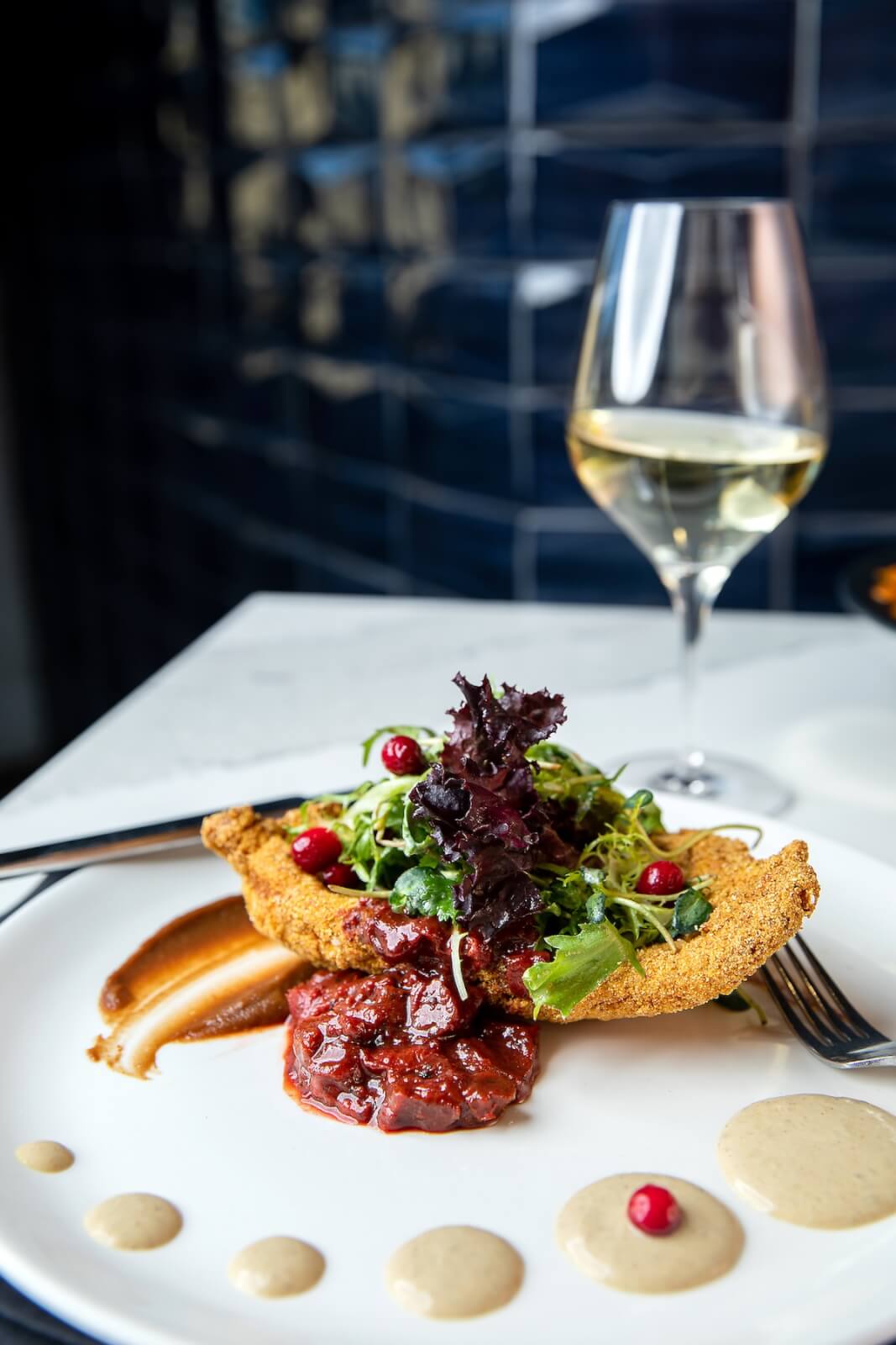 Plate of food on table with a glass of white wine.