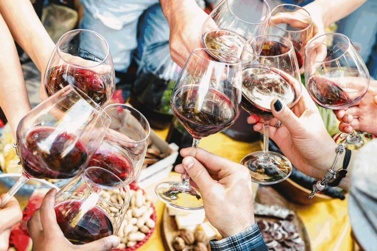 Amidst the lively buzz of April events in Nashville, a group of people clinks glasses of red wine over a table adorned with assorted snacks.