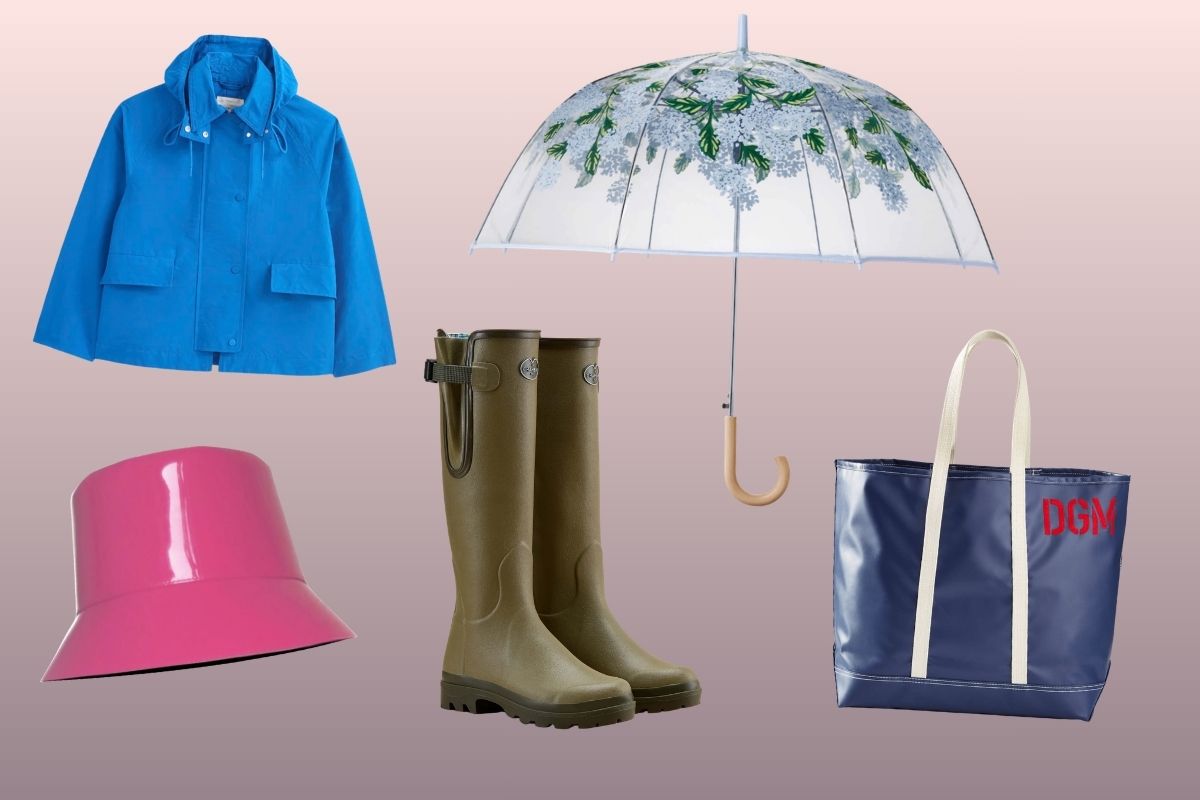 A blue rain coat, pink bucket hat, green rain boots, translucent umbrella with leaf pattern, and a navy tote bag with white straps and red initials "DGM.