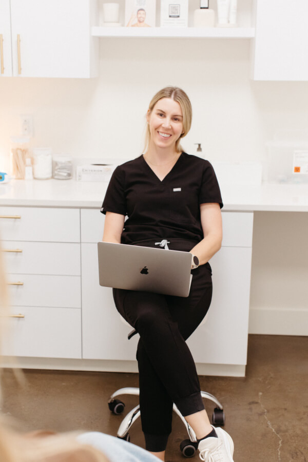 A woman sitting in a chair with a laptop on her lap.