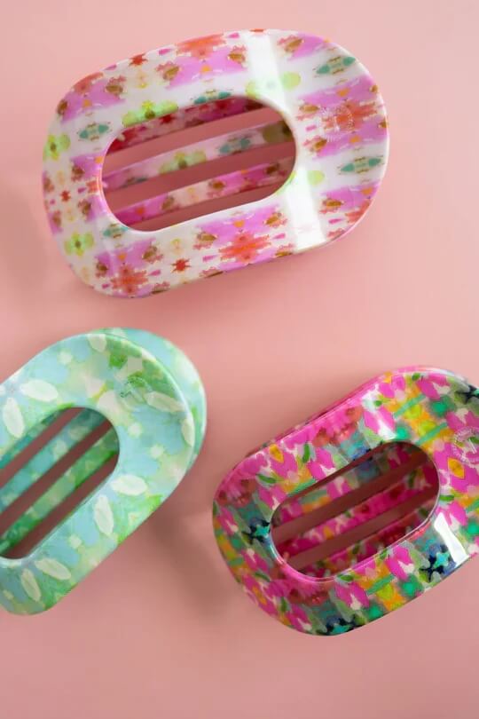 Discover March FINDS with these three colorful, oval-shaped hair clips featuring vibrant floral patterns against a pink background.