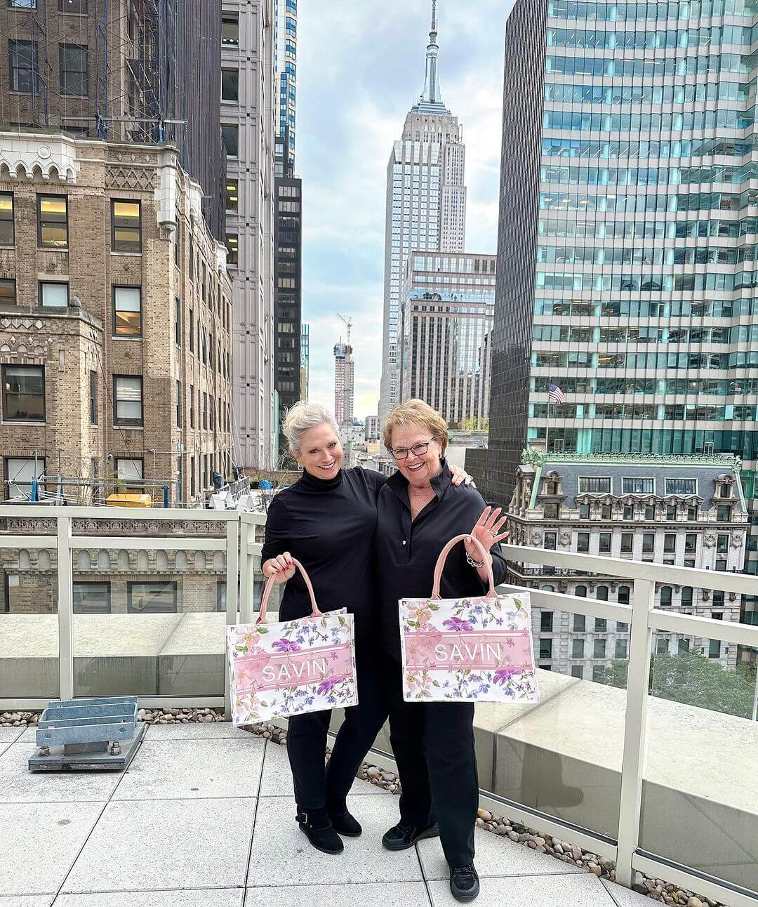 Cathy and Carolyn Kelley on a rooftop in New York City, holding shopping bags, with the Empire State Building in the background.