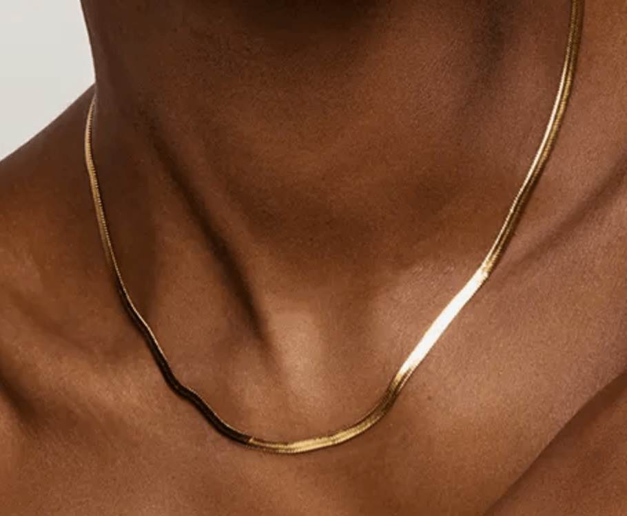 Close-up of a gold necklace on the collarbone of a person