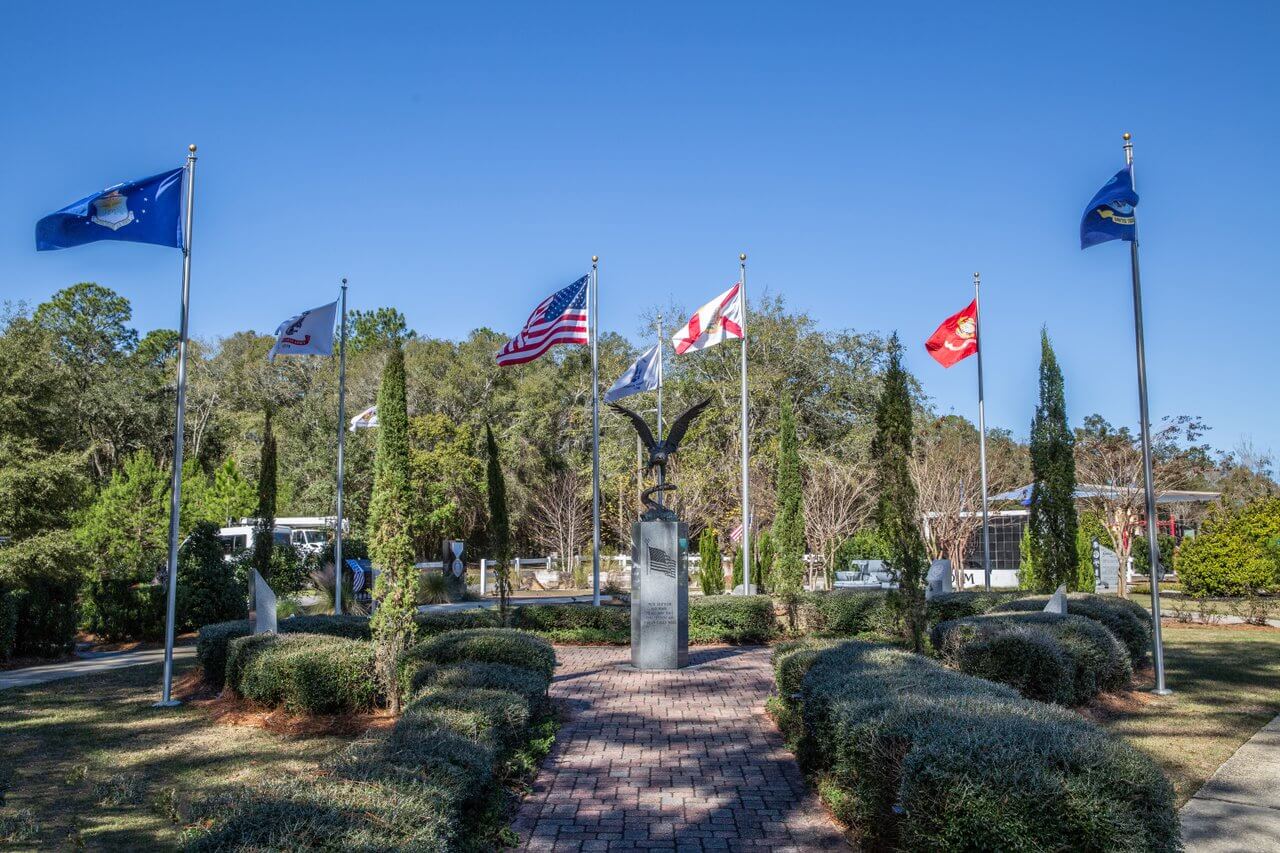 Flag-lined walkway leading to a metal eagle sculpture in a park setting, among the things to do near 30a.