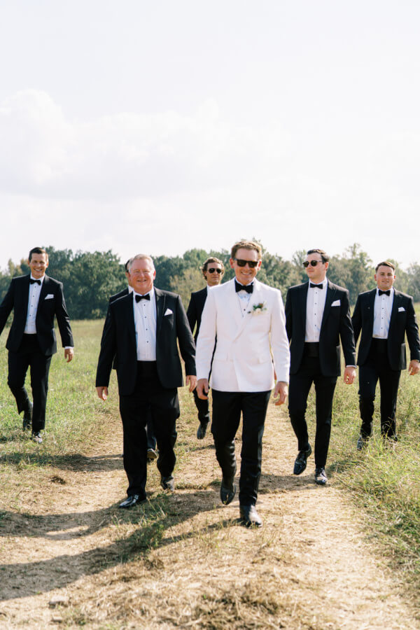 A group of men in formal attire walking confidently across a field.
