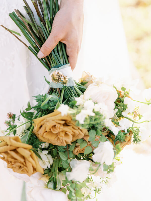 A bride holding a bouquet of white and pale yellow flowers.