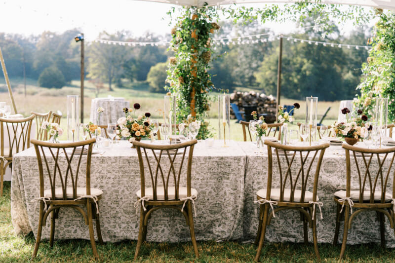 Elegant outdoor wedding setup with decorated tables and string lights.