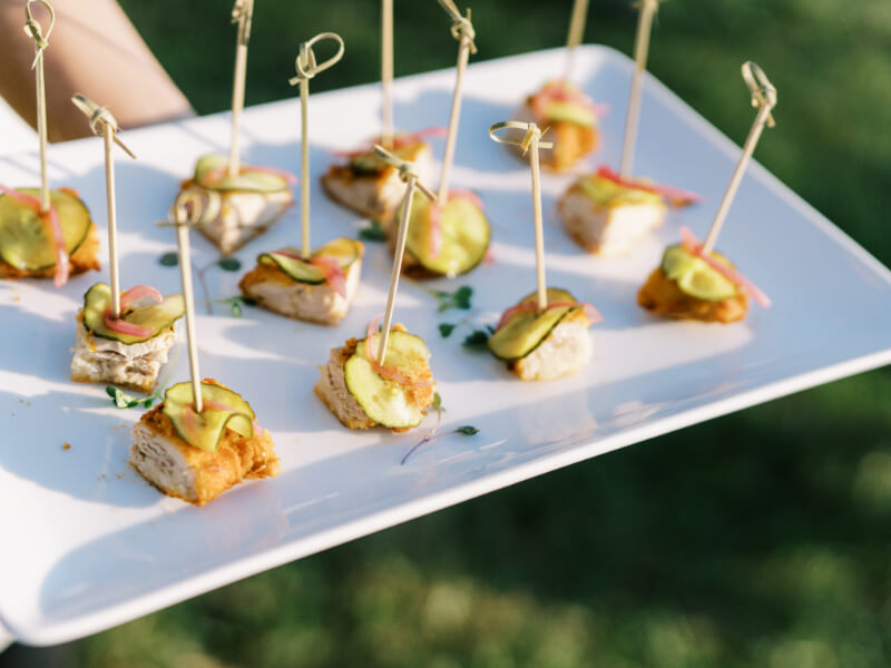 A tray of appetizers with avocado slices and dipping sauce, presented with toothpicks for easy serving.