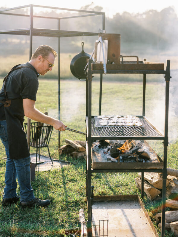 Man grilling food outdoors on a sunny day.