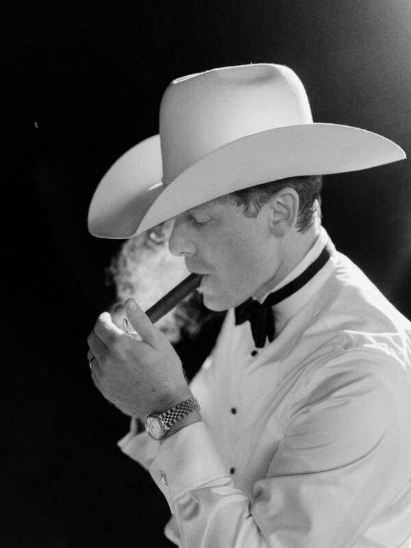 Man in a white hat lighting a cigar.