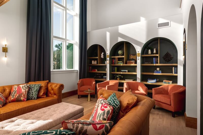 9 Boutique Hotels on the Emerald Coast - 7 A stylish living room with terracotta sofas, patterned cushions, arched bookshelves inspired by 30a hotels, and sunlit windows.