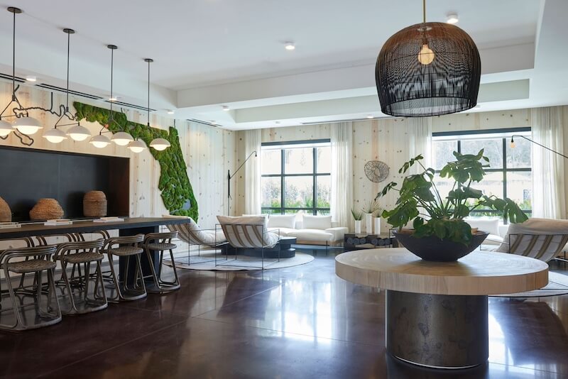 9 Boutique Hotels on the Emerald Coast - 9 Modern, spacious hotel living room with a kitchen bar, large windows, hanging lamps, and a blend of cozy and stylish furniture.
