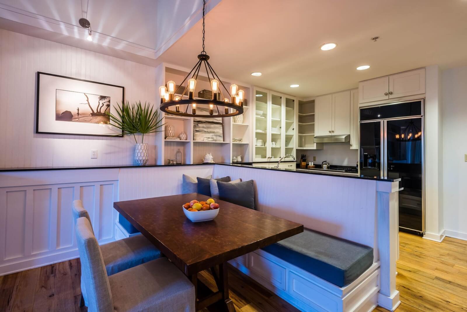 9 Boutique Hotels on the Emerald Coast - 15 Modern kitchen with white cabinetry and built-in dining nook featuring a wooden table framed by pendant lighting, resembling the elegant design found in 30a hotels.