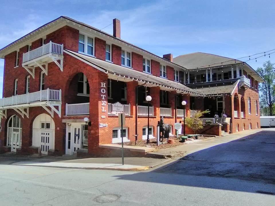 A large, red-brick, two-story building with "HOTEL" written vertically on the corner. The structure features multiple balconies and a small sign protruding from the corner, ideal for those seeking retreats in South Carolina.