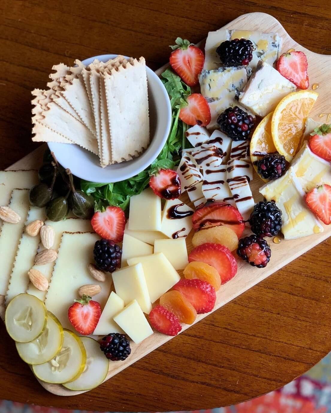 5 Local Experiences Every Memphian Should Try - 1 A cheese board with various cheeses, crackers, fruit, nuts, pickles, and drizzled sauce on a wood tray.