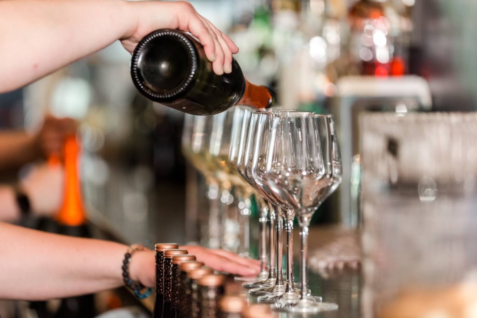 5 Local Experiences Every Memphian Should Try - 2 A person pours wine into multiple empty wine glasses lined up on a bar counter.