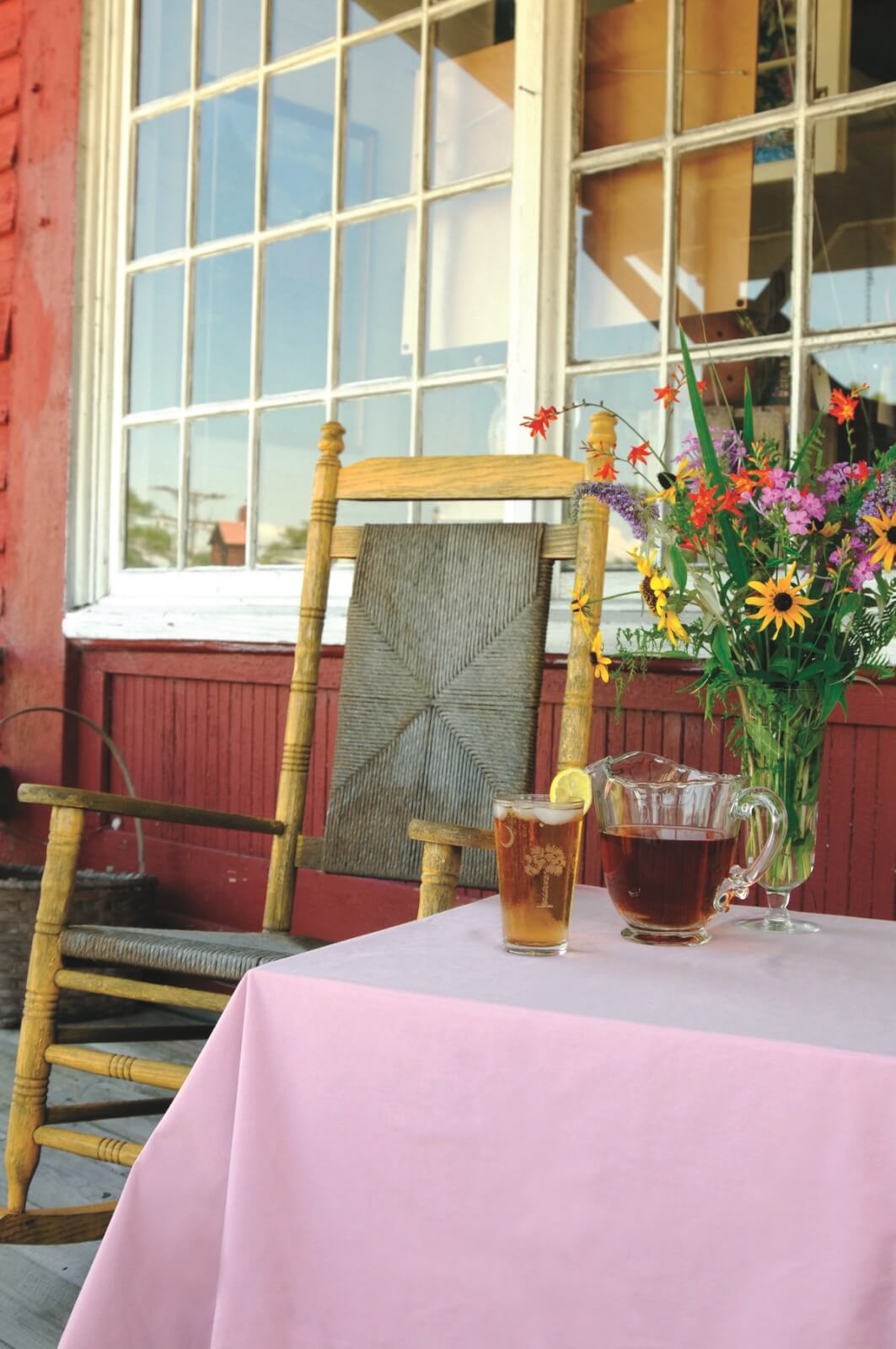 Front porch with rocking chair and pink table with iced tea.