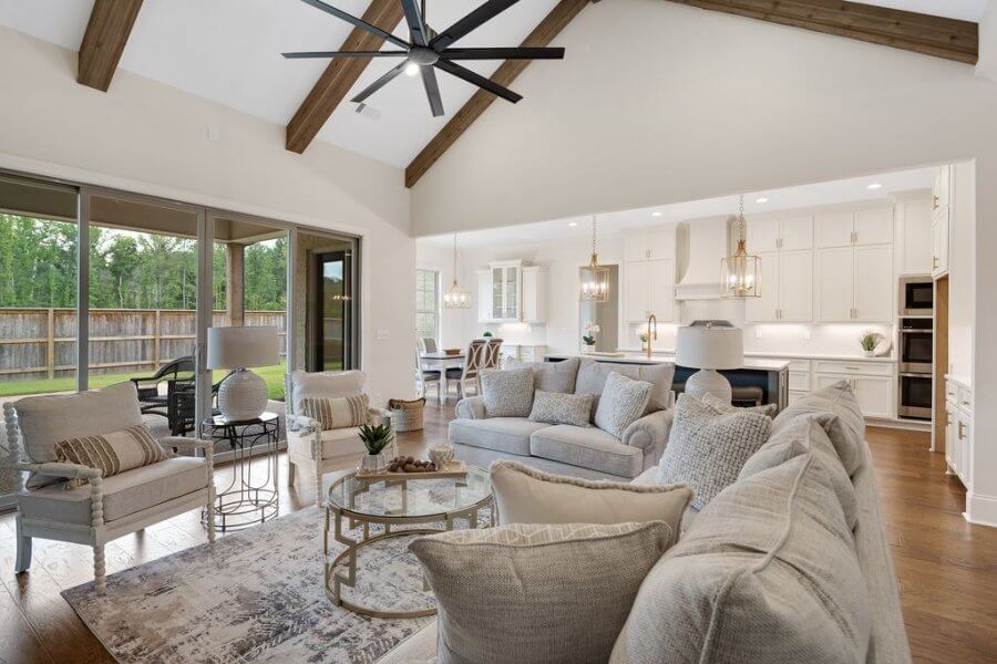 Spacious open-concept living room and kitchen with neutral décor, vaulted ceiling with wooden beams, large windows, and modern furnishings on Magnolia Ridge Drive in Rossville, Tennessee.