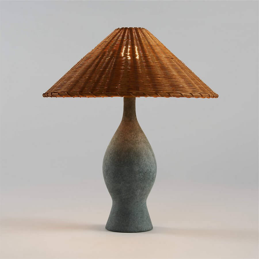 A table lamp with a textured, gray ceramic base and a woven, conical rattan lampshade, beautifully illuminated against a plain background.