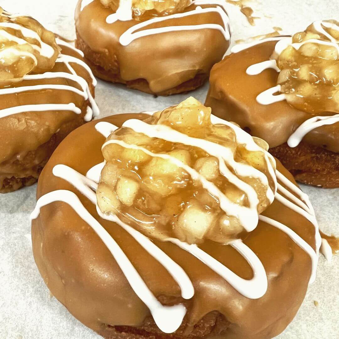 Close-up of caramel-glazed donuts topped with apple pie filling and drizzled with white frosting, a delicious highlight among the new menus at Louisville restaurants.
