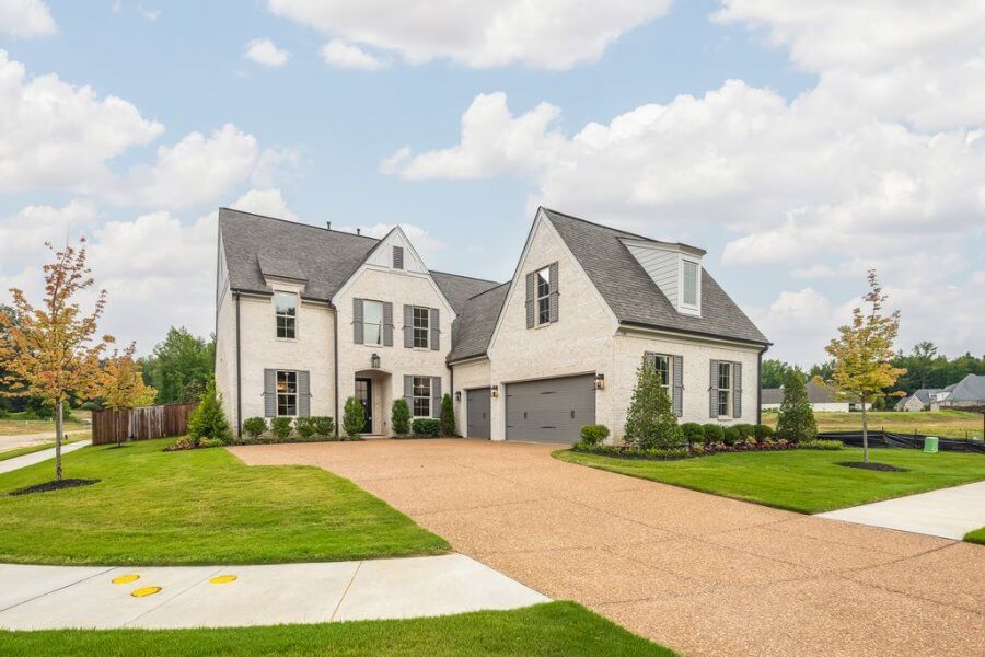 A two-story suburban house on Magnolia Ridge Drive in Rossville, Tennessee, with a white brick exterior, black shutters, gray garage doors, and a spacious driveway, surrounded by manicured lawn and young trees.