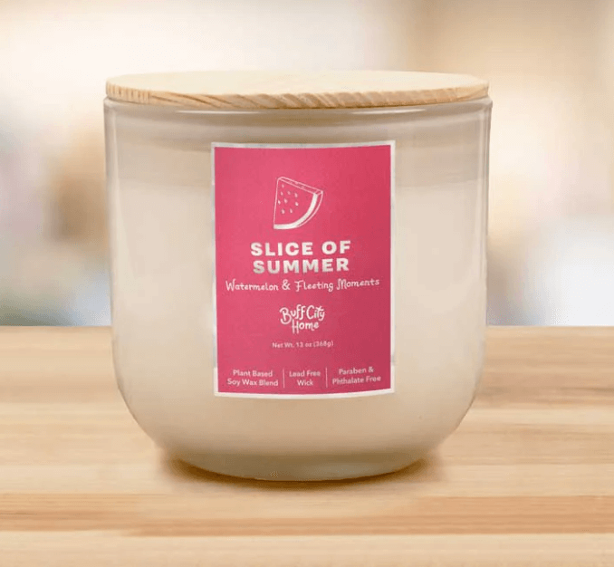 17 Birmingham FINDS Perfect for Summer - 14 A white candle in a glass container with a wooden lid. The label reads "Slice of Summer: Watermelon & Fleeting Moments" from Buff City Home.